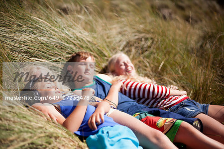 Four friends relaxing in dunes, Wales, UK