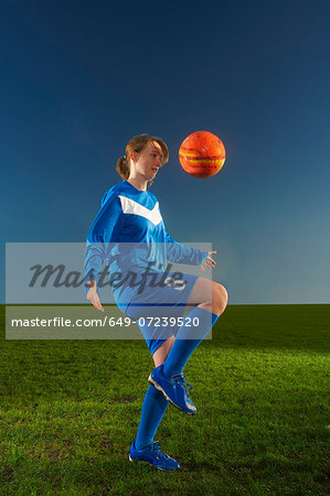 Female footballer playing keepy uppy with ball