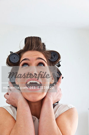 Young woman wearing hair rollers looking up