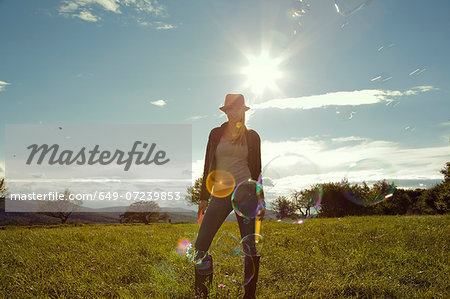 Young woman in field with blown bubbles