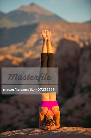 Young woman doing headstand, Moab, Utah, USA