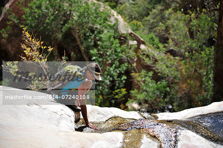 Female hiker crouching on rock, Mount Wilson, Red Rock Canyon, Nevada, USA