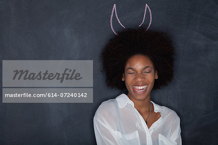 Young woman by blackboard with horns