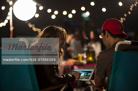 Young couple looking at digital tablet at rooftop barbecue Young couple looking at digital tablet at rooftop barbecue