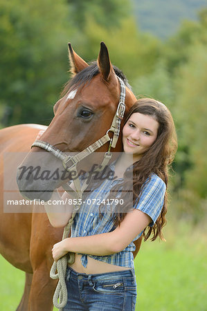 Teenage girl standing with a Mecklenburger horse on a paddock