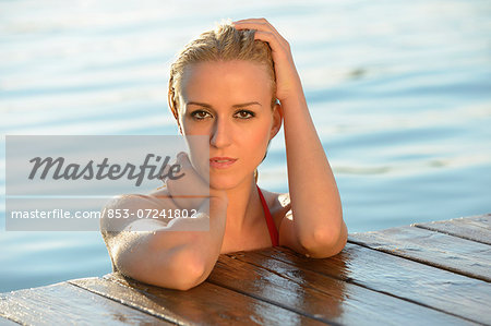 Young blond woman at a jetty at a lake, Styria, Austria