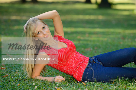 Young blond woman lying in a park