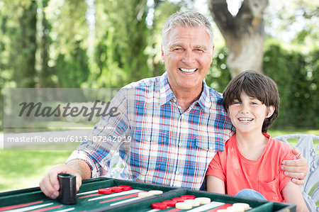 Grandfather and grandson playing backgammon on patio
