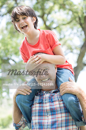 Grandfather carrying grandson on shoulders outdoors