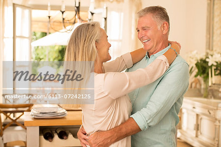 Senior couple hugging in kitchen