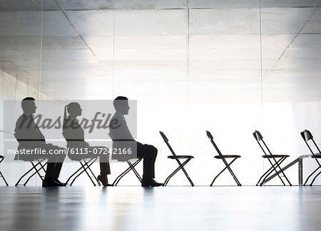 Business people sitting in office chairs in a row