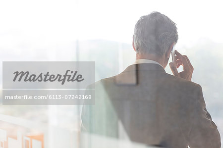 Businessman talking on cell phone in office Businessman talking on cell phone in office