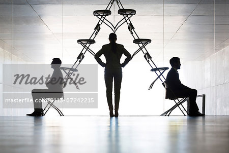 Businesswoman examining office chair installation art Businesswoman examining office chair installation art