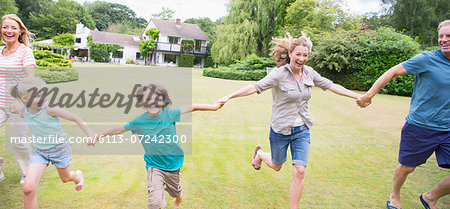 Multi-generation family holding hands and running in backyard