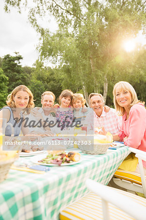 Multi-generation family eating lunch at table in backyard