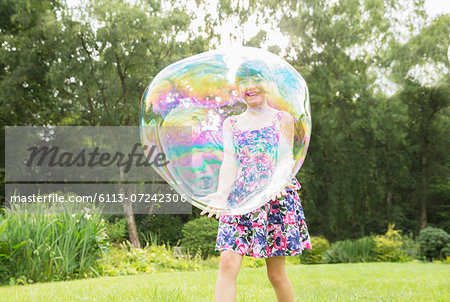 Father and daughter playing with large bubbles in backyard