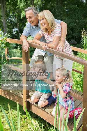 Grandparents and grandchildren smiling on wooden footbridge