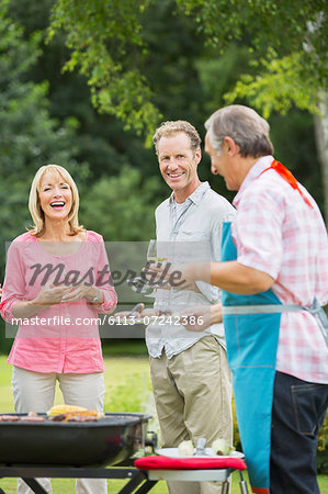 Family standing at barbecue in backyard