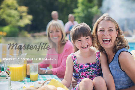 Multi-generation family laughing at table in backyard