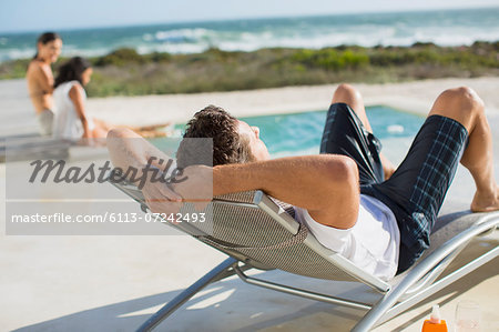 Man relaxing in lounge chair at poolside
