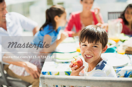 Boy eating fruit with family at table on sunny patio