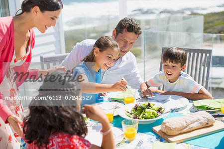 Family eating lunch at table on sunny patio