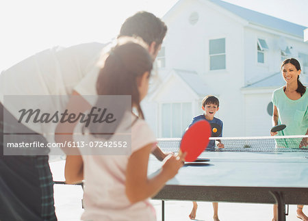 Family playing table tennis outside house