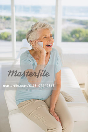 Senior woman talking on cell phone in living room