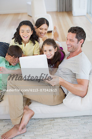 Family using laptop on sofa in living room Family using laptop on sofa in living room