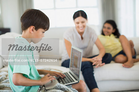 Boy using laptop on sofa in living room