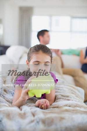 Girl counting change in piggy bank on sofa in living room