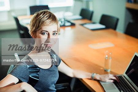 Businesswoman using laptop at conference table