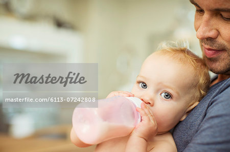 Father feeding baby in kitchen