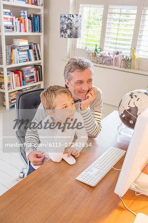 Father and son using computer together