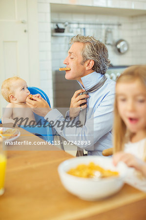 Father and children eating breakfast in kitchen