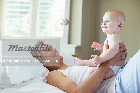 Father playing with baby on bed