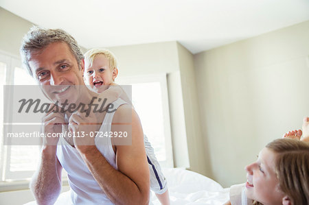 Father and children playing on bed