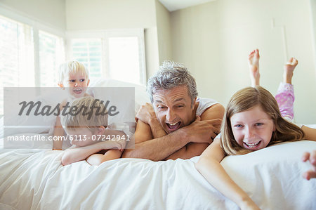 Father and children relaxing on bed