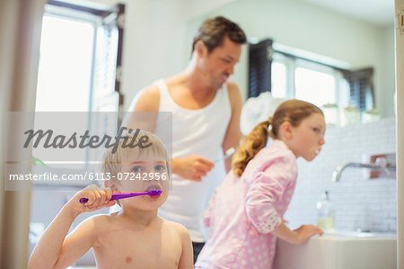 Father and children brushing teeth in bathroom