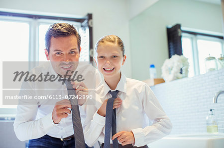 Father and daughter adjusting ties in bathroom