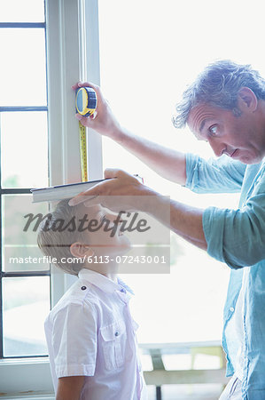 Father measuring son's height on wall Father measuring son's height on wall