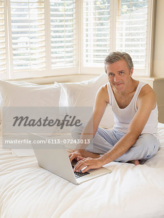 Man using laptop on bed