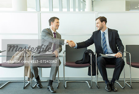 Businessmen shaking hands in waiting area
