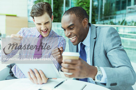 Businessmen cheering at digital tablet