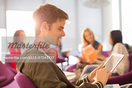 University student using digital tablet in lounge