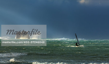 A surfer rides the storm, near the sunken ship