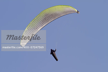 A paraglider falling from the sky with his parachute