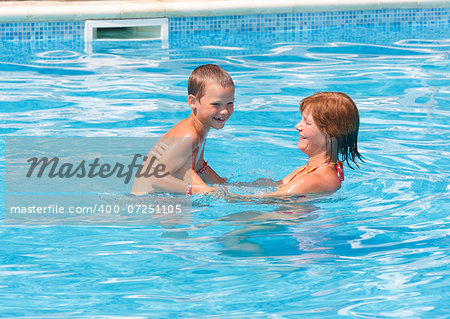 Mother with her son in the summer outdoor pool.
