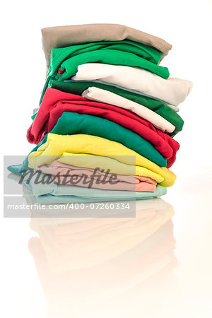 Colorful T-shits stacked together. White background and light reflection in front