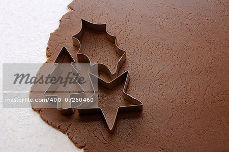 Cutting out Christmas tree, holly leaf and star shapes from gingerbread dough